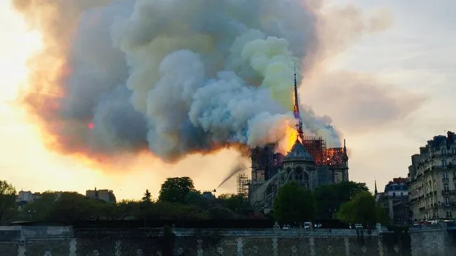 Notre-Dame de Paris en feu, panache de fumée au-dessus de la toiture, vue depuis les quais de Seine